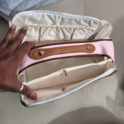 Pink handbag with a visible brand logo held by a person against a light background